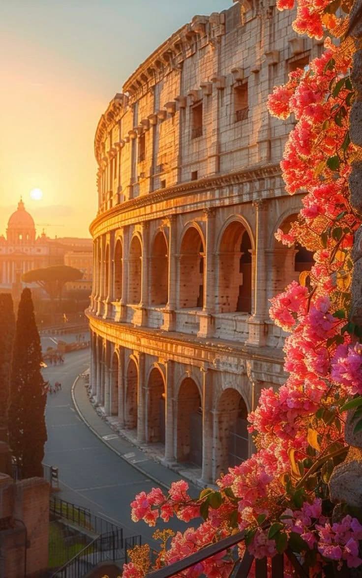 The Colosseum in Rome at golden hour framed by pink flowers.